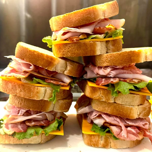 Stacked deli sandwiches with ham, bacon, cheese, and lettuce on toasted bread from Flurry's Market Lakeside.