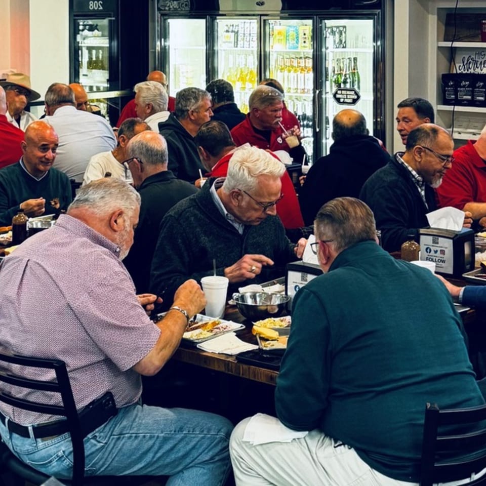 Diners enjoying meals at tables inside Flurry’s Market Lakeside, with deli refrigerators in the background.