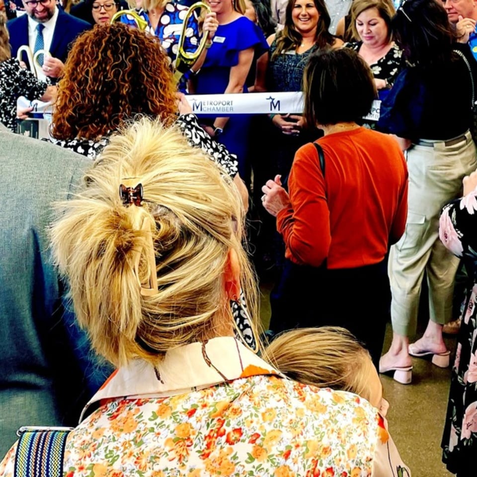 People gathered for a ribbon-cutting ceremony, with a "Metroport Chamber" banner visible.