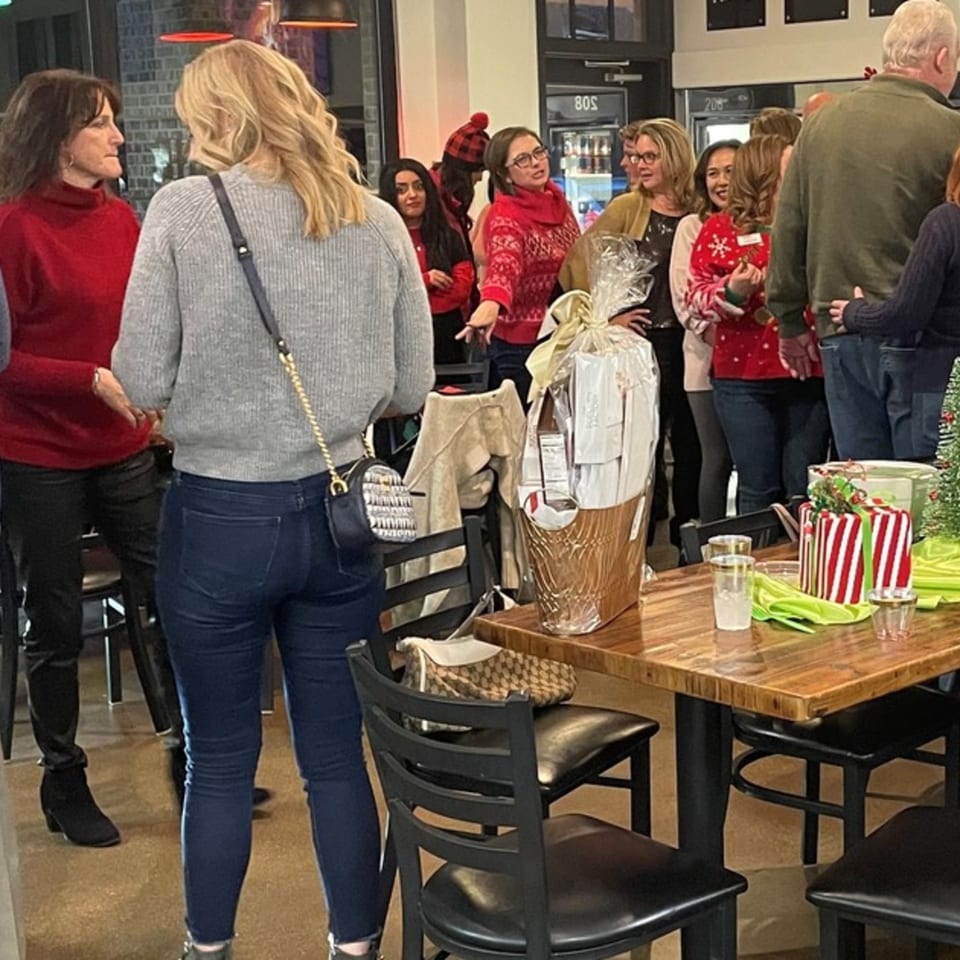 Guests mingle at Flurry's Market Lakeside, with festive decorations and gift baskets on tables.